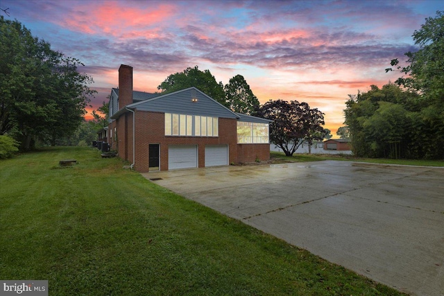 property exterior at dusk with a garage and a lawn