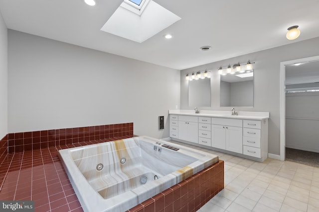 bathroom featuring tiled tub, vanity, a skylight, and tile patterned floors