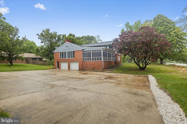 view of property exterior with a garage, a sunroom, and a lawn