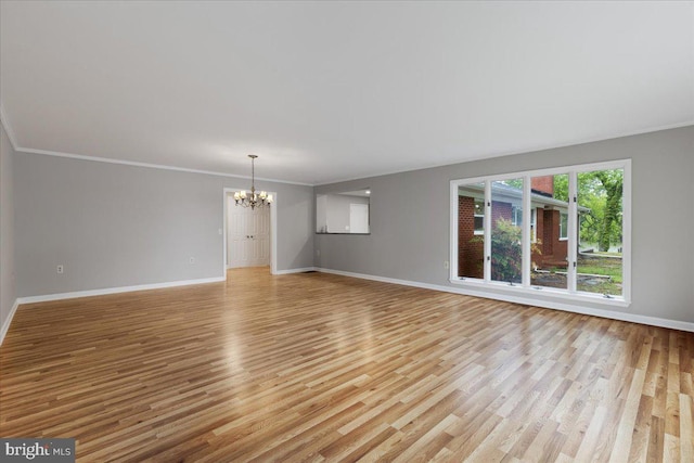 unfurnished living room featuring crown molding, light hardwood / wood-style floors, and a chandelier