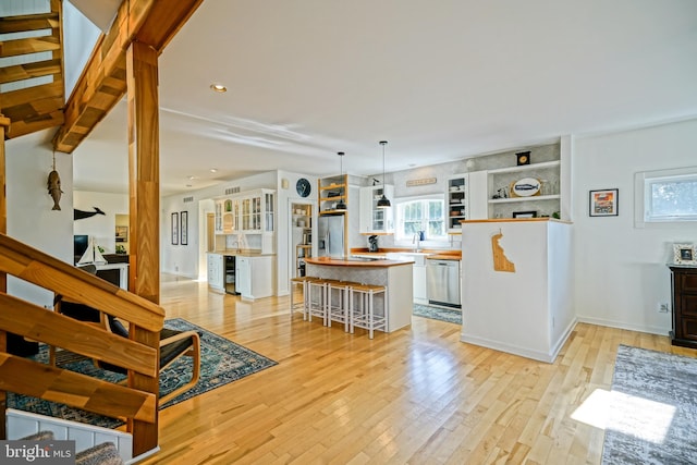 kitchen featuring light hardwood / wood-style flooring, stainless steel appliances, a center island, a kitchen bar, and pendant lighting