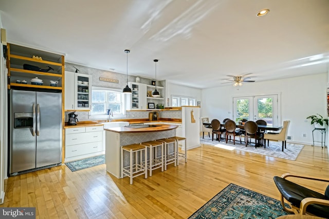 kitchen with stainless steel fridge, light hardwood / wood-style flooring, decorative light fixtures, and white cabinetry