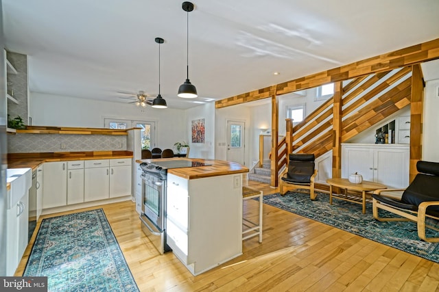 kitchen with wooden counters, light hardwood / wood-style flooring, electric stove, white cabinetry, and ceiling fan