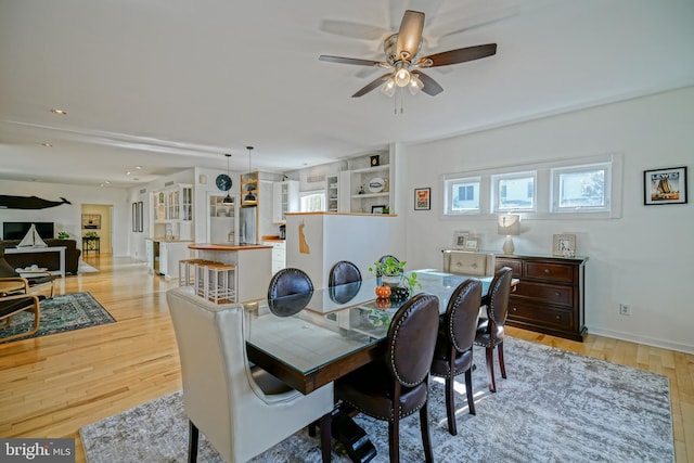 dining room with built in features, light hardwood / wood-style floors, and ceiling fan