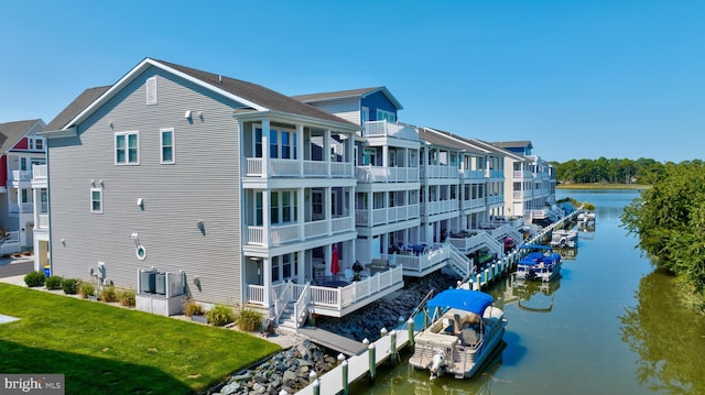 exterior space featuring a balcony, a water view, and a lawn