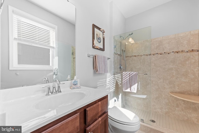 bathroom featuring vanity, a tile shower, and toilet