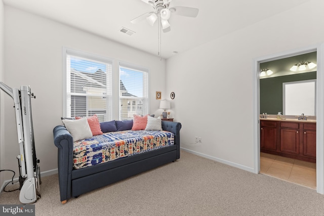 bedroom featuring light carpet, ensuite bath, sink, and ceiling fan