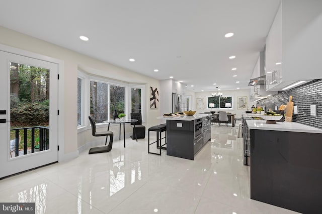 kitchen featuring a spacious island, appliances with stainless steel finishes, a breakfast bar, light countertops, and backsplash