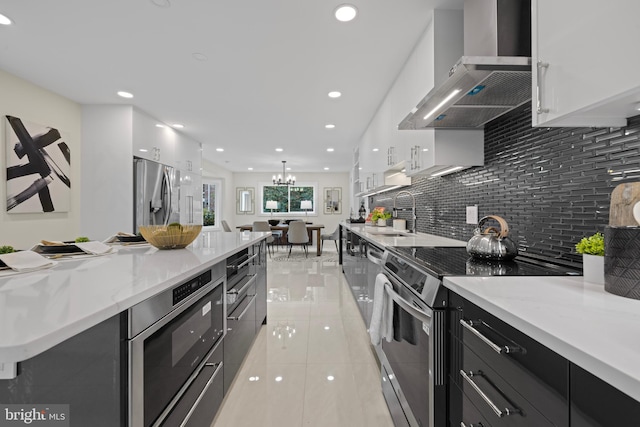 kitchen with white cabinets, wall chimney range hood, sink, appliances with stainless steel finishes, and tasteful backsplash