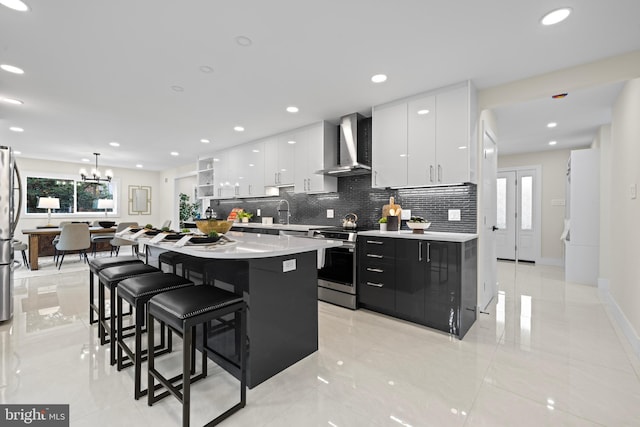 kitchen with white cabinetry, hanging light fixtures, stainless steel appliances, wall chimney range hood, and backsplash