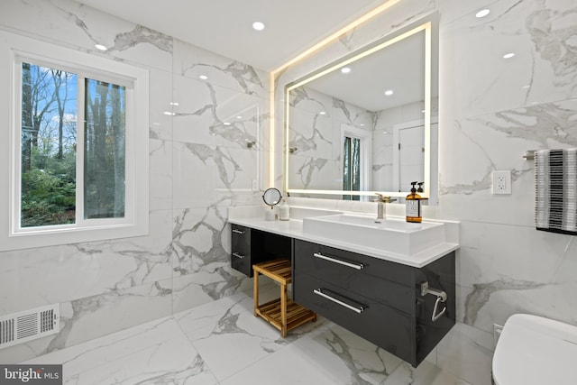 bathroom featuring stone wall and visible vents