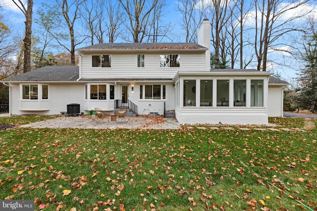 view of front of home featuring central AC, brick siding, a sunroom, a front lawn, and a chimney