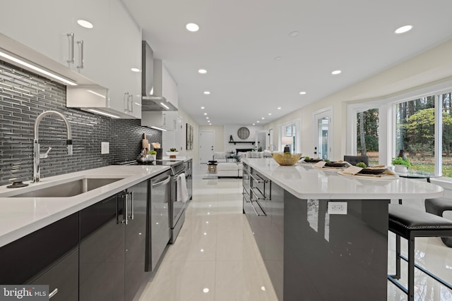 kitchen with modern cabinets, stove, open floor plan, wall chimney range hood, and a sink