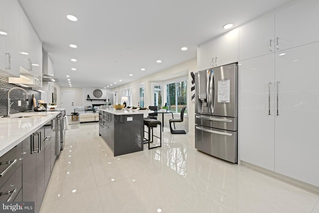 kitchen featuring modern cabinets, stainless steel refrigerator with ice dispenser, a sink, and open floor plan