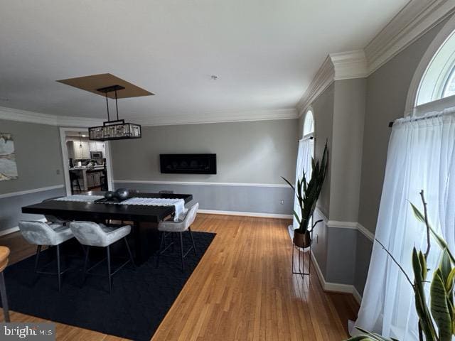 dining space with hardwood / wood-style flooring and crown molding