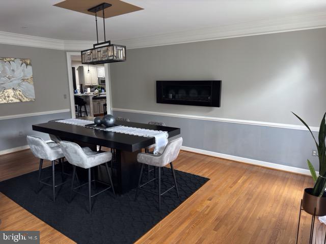 dining space featuring wood-type flooring and ornamental molding