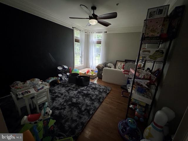 interior space with dark wood-type flooring, ornamental molding, and ceiling fan