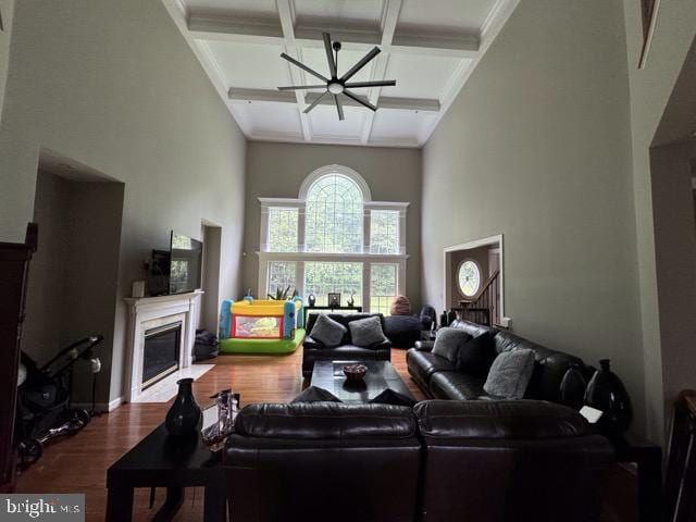 living room with beamed ceiling, ceiling fan, dark hardwood / wood-style flooring, coffered ceiling, and ornamental molding