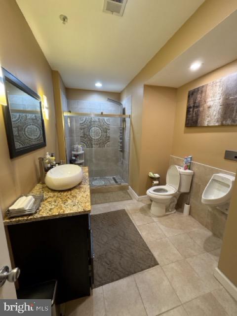 bathroom with a shower with door, tile patterned floors, vanity, and toilet