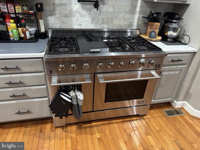 kitchen featuring backsplash, light hardwood / wood-style floors, and double oven range