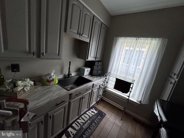 kitchen featuring light stone counters, dark wood-type flooring, and sink