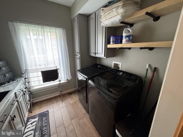 laundry area with washer and clothes dryer and light hardwood / wood-style floors