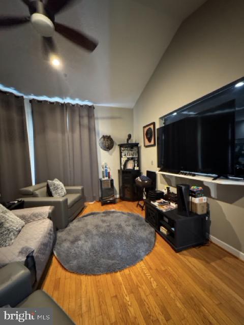 living room with lofted ceiling, hardwood / wood-style flooring, and ceiling fan