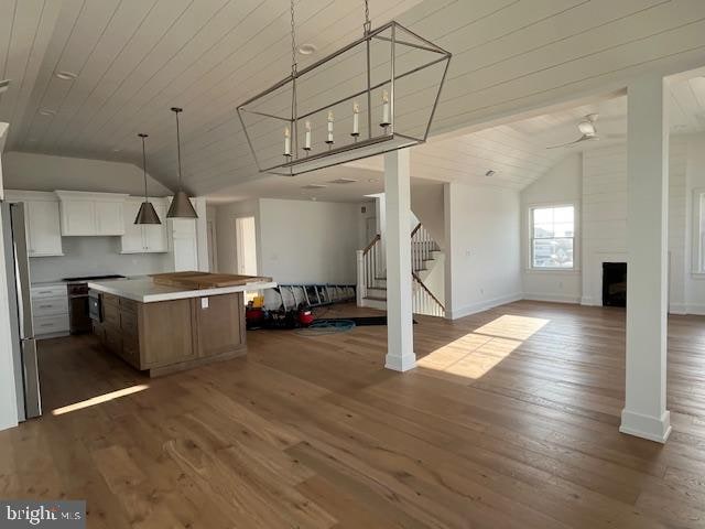 kitchen with pendant lighting, a center island, white cabinets, a large fireplace, and stainless steel refrigerator