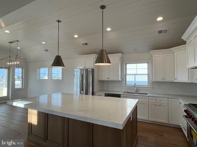 kitchen featuring a center island, stainless steel appliances, white cabinetry, and sink