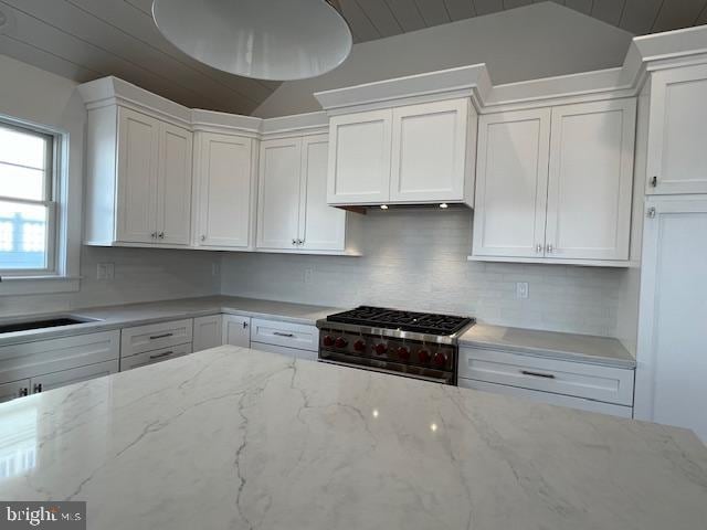 kitchen featuring white cabinetry, stainless steel range, and vaulted ceiling