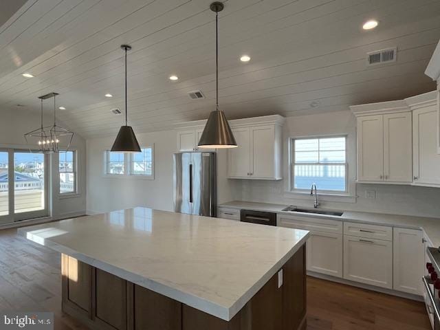 kitchen with a center island, white cabinetry, stainless steel refrigerator, and sink