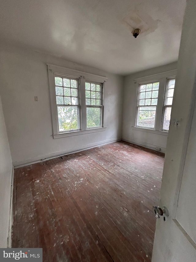 spare room featuring wood-type flooring and baseboards