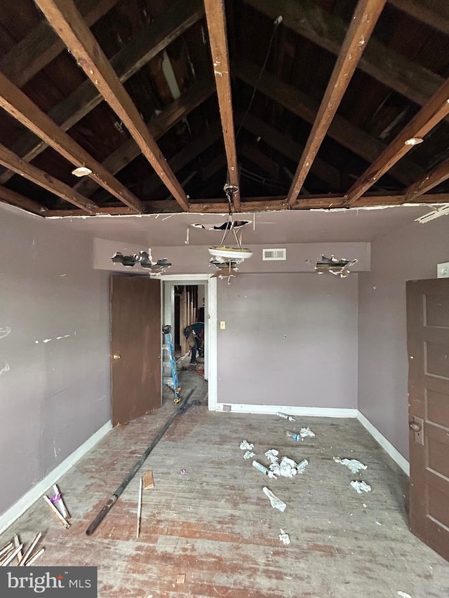 empty room featuring vaulted ceiling, visible vents, and baseboards