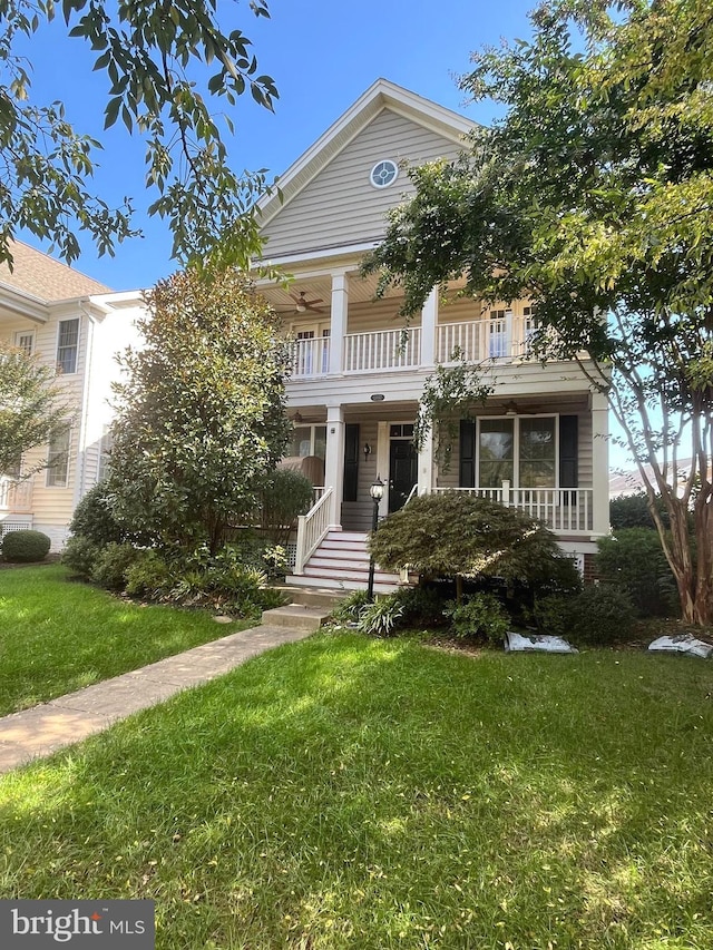 neoclassical home with a front yard, a balcony, and covered porch