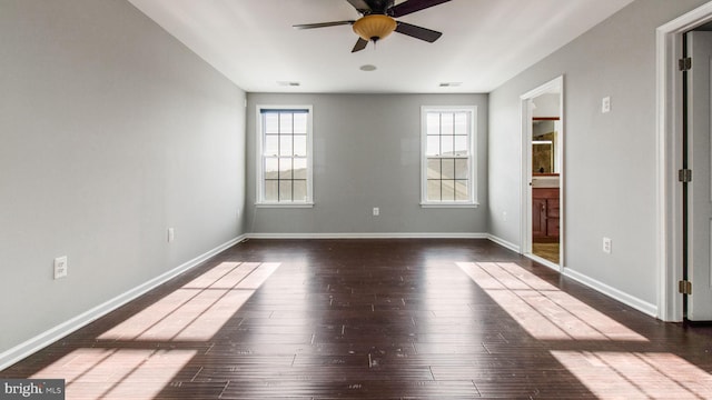 empty room featuring a healthy amount of sunlight, dark wood-type flooring, and ceiling fan