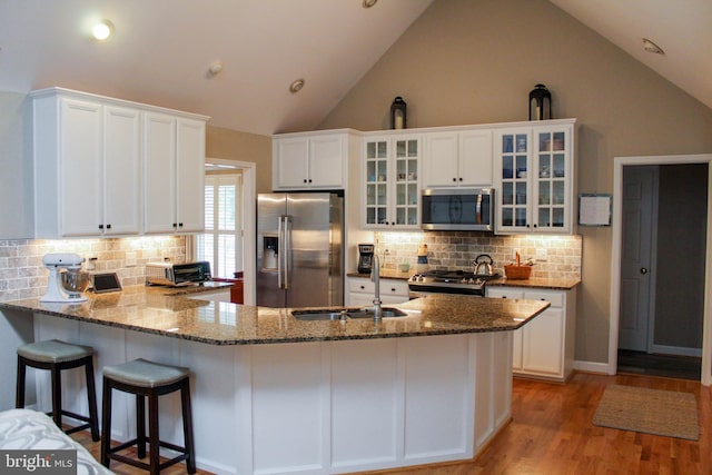 kitchen featuring appliances with stainless steel finishes, tasteful backsplash, white cabinets, light wood-type flooring, and sink