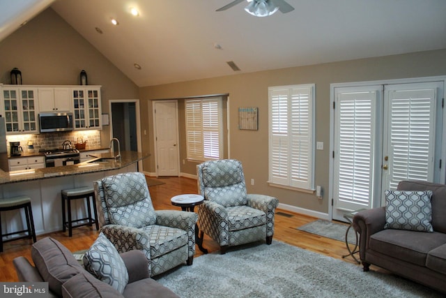 living room featuring ceiling fan, sink, lofted ceiling, and light hardwood / wood-style floors