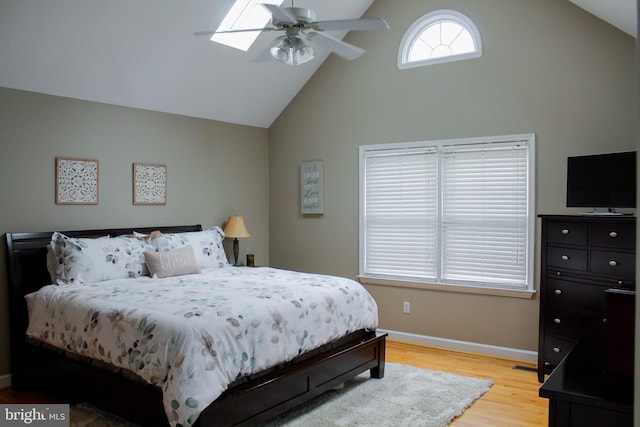 bedroom featuring ceiling fan, vaulted ceiling with skylight, and light hardwood / wood-style flooring