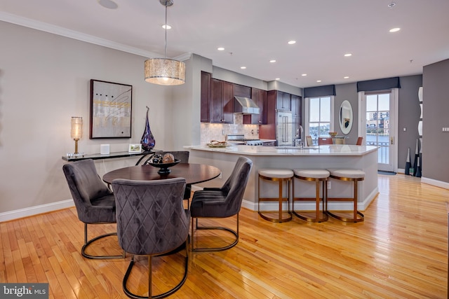 dining space with crown molding, sink, and light wood-type flooring