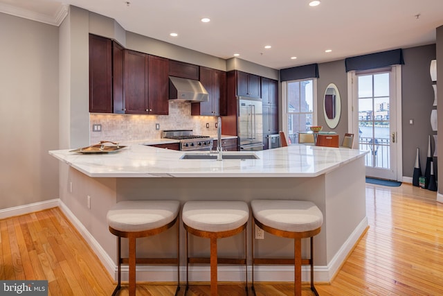 kitchen with stainless steel built in fridge, kitchen peninsula, backsplash, ventilation hood, and light hardwood / wood-style floors