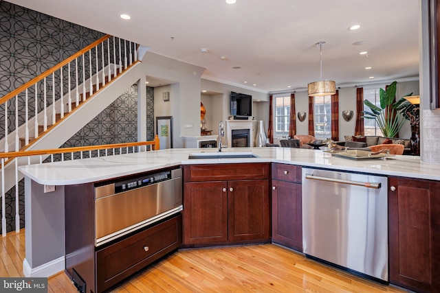 kitchen featuring stainless steel dishwasher, pendant lighting, light hardwood / wood-style floors, crown molding, and sink