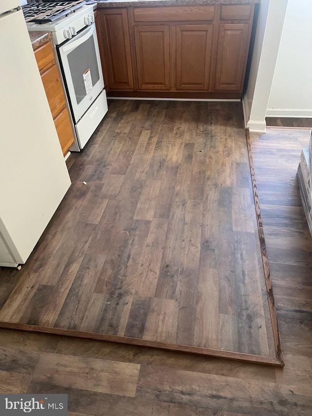 kitchen with refrigerator, white gas stove, and dark hardwood / wood-style flooring