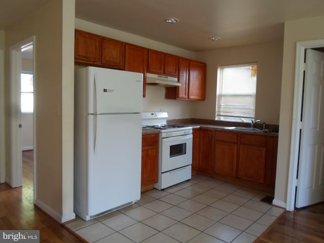 kitchen with white appliances, light tile patterned floors, and sink