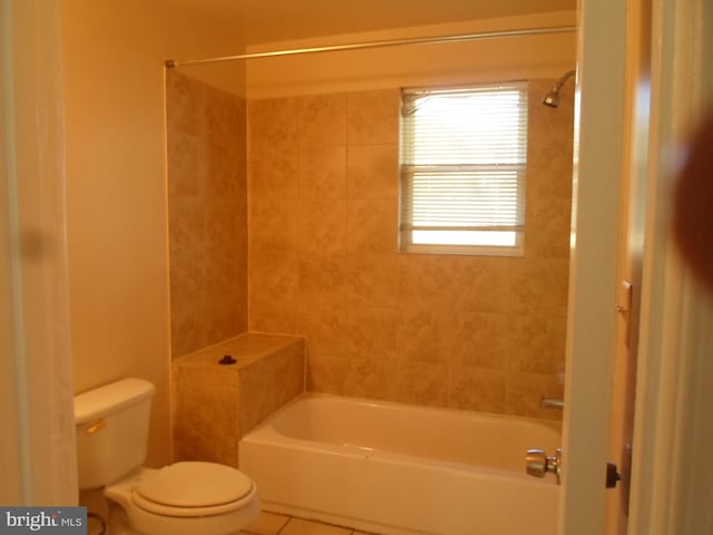 bathroom with toilet, tiled shower / bath, and tile patterned flooring