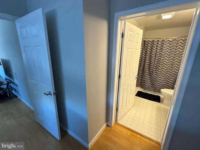 bathroom with hardwood / wood-style flooring, toilet, and a shower with curtain