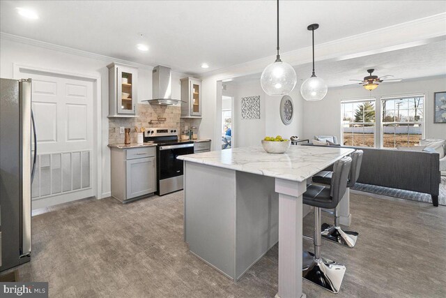 kitchen featuring appliances with stainless steel finishes, a kitchen island, hanging light fixtures, wall chimney exhaust hood, and gray cabinets