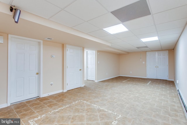 basement featuring a baseboard heating unit and a paneled ceiling