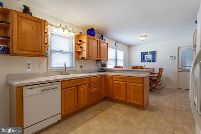 kitchen featuring a wealth of natural light, white dishwasher, kitchen peninsula, and sink