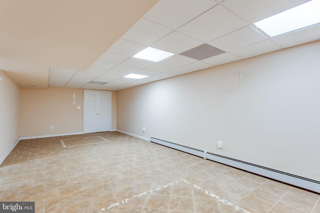 basement with a baseboard radiator and a drop ceiling