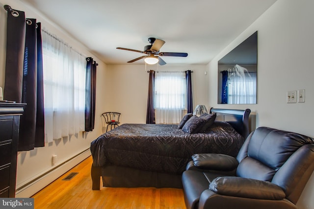 bedroom with ceiling fan, hardwood / wood-style flooring, and baseboard heating